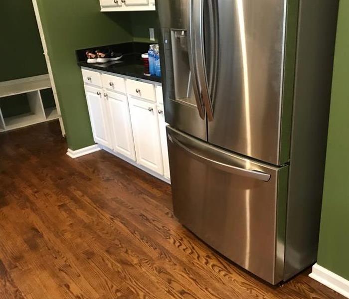 The damaged kitchen has a fresh coat of paint, cabinets and flooring reinstalled and the refrigerator reconnected.